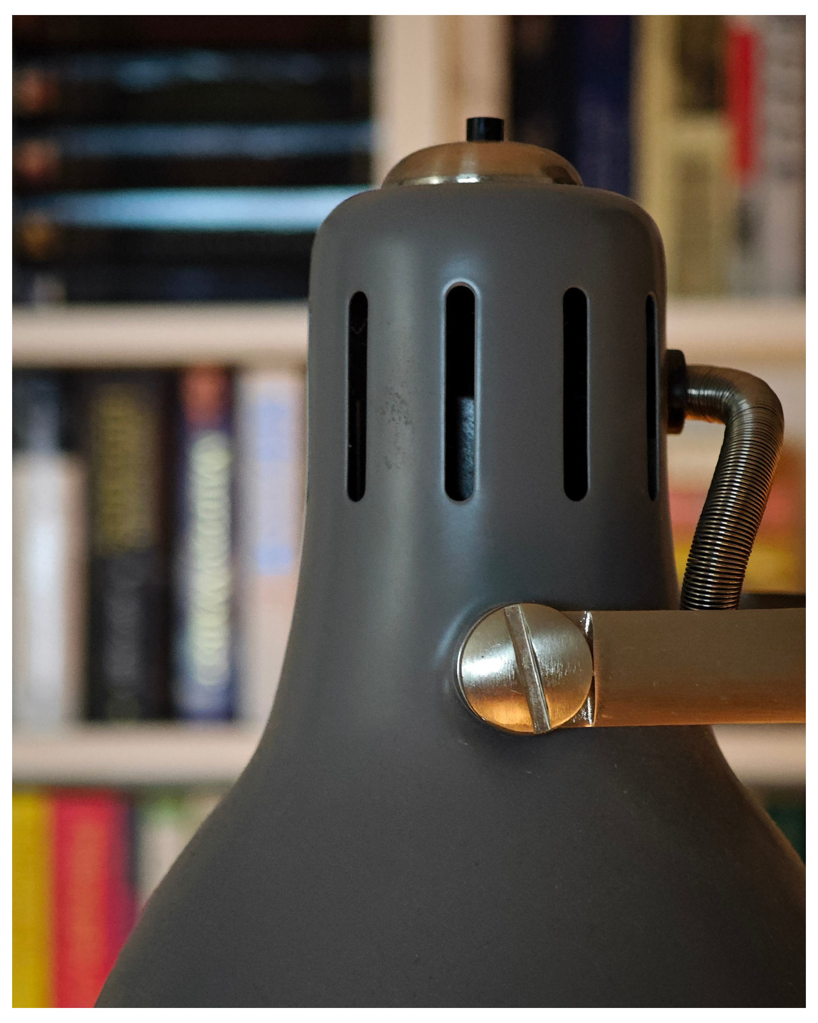 Close up of a reading lamp with an out of focus bookcase in the background