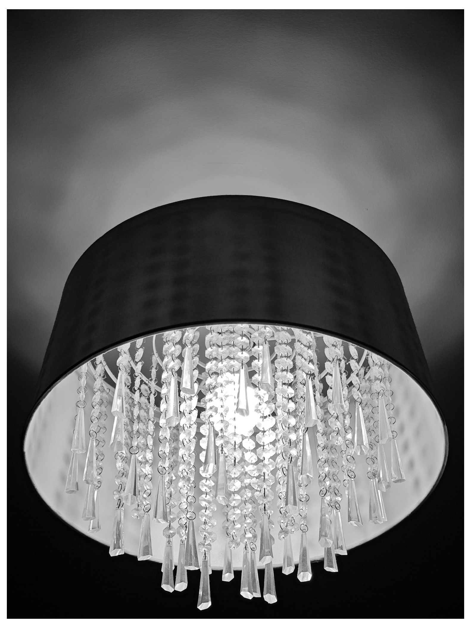 Image of a crystal style light fitting with shade and reflection on ceiling